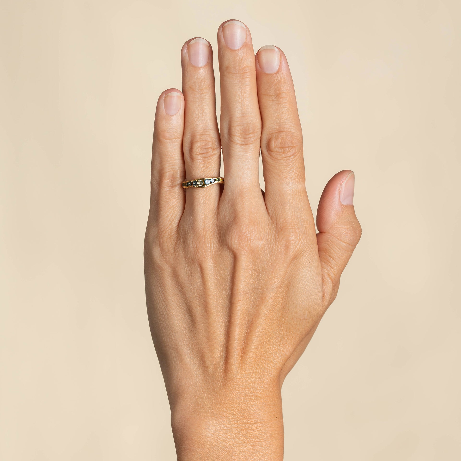 An irregular channel forms a valley of solid band of 18ct yellow gold, natural sapphires nestling in the sea worn crease. By Emily Nixon.