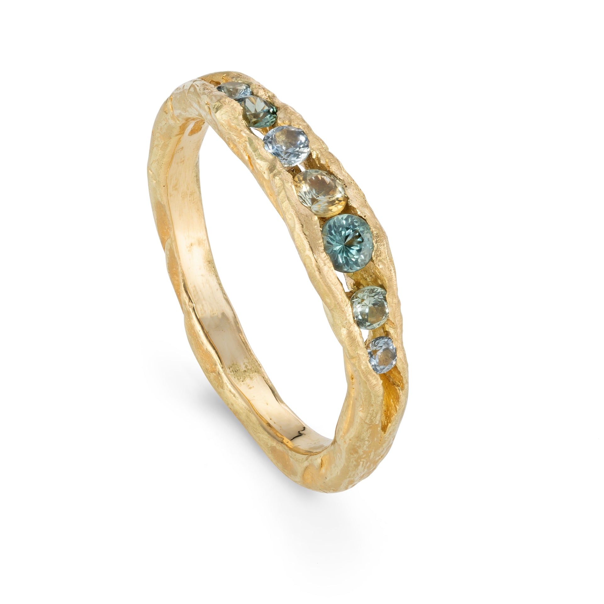 An irregular channel forms a valley of solid band of 18ct yellow gold, natural sapphires nestling in the sea worn crease. By Emily Nixon.