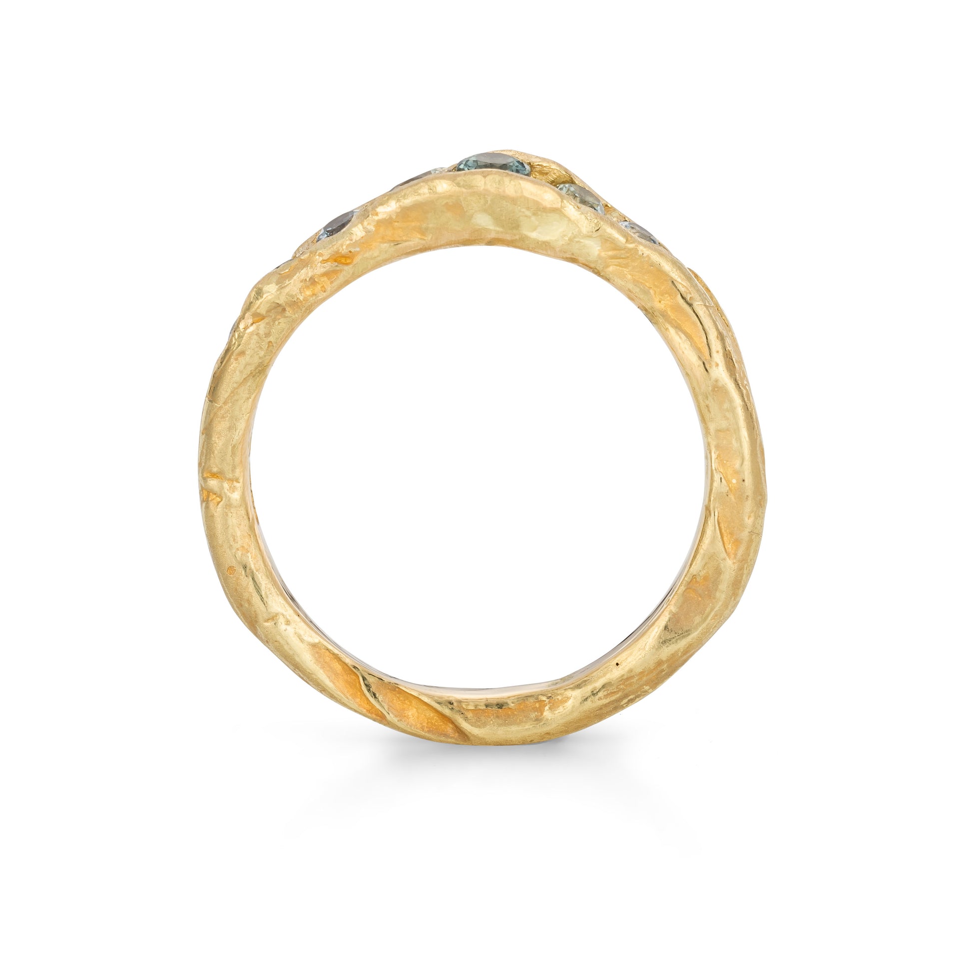 An irregular channel forms a valley of solid band of 18ct yellow gold, natural sapphires nestling in the sea worn crease. By Emily Nixon.