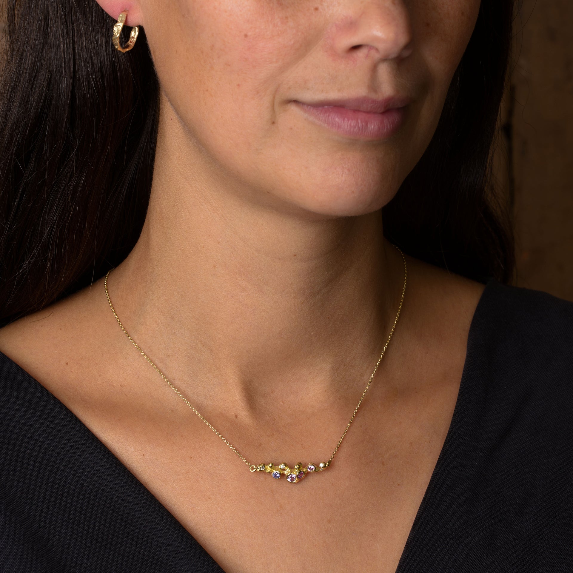 Organic gold, sapphire and diamond pendant by Emily Nixon. On a delicate gold chain, this piece is handcrafted in Cornwall and seen worn on a model.