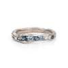 A channel forms a valley in this solid band of 18ct white gold, natural teal sapphires nestling in the sea worn crease. By Emily Nixon.