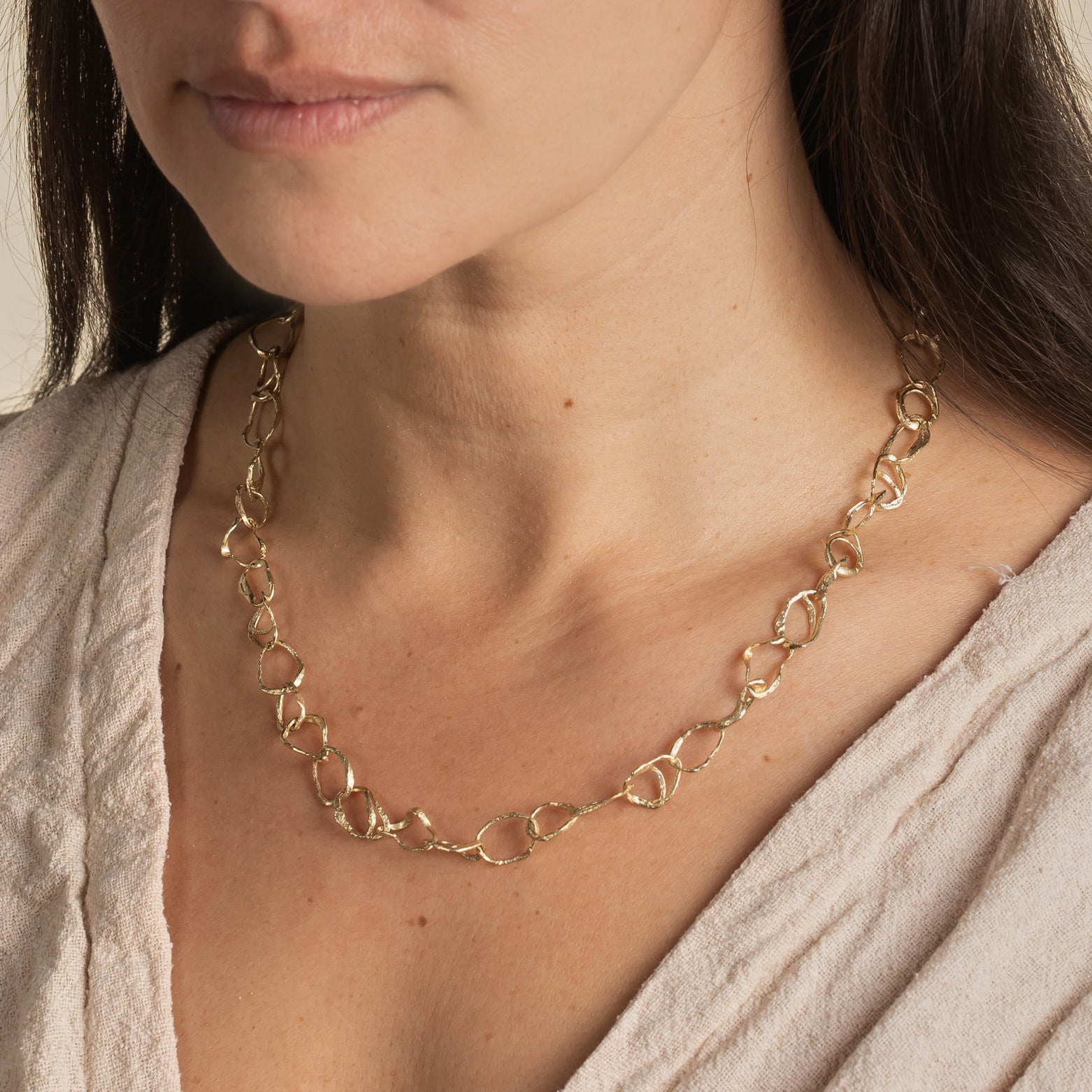 Contemporary jewellery necklace designed by Cornish jeweller Emily Nixon. Fine - approx 1cm across - irregular gold links are interconnected to create a long gold link chain. The style of Emily’s coastal jewellery is artful, organic and distinctly handmade. The links have been formed from small smoothed pebbles from Cornwall’s beaches creating the unusual, natural character of the necklace. Can be worn at long choker length 52cm or a medium length chain at 62cm. 