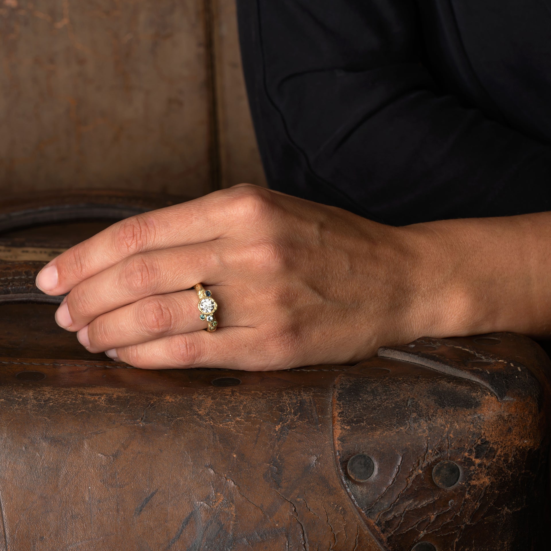 Rock pool sapphires perch around a pool of diamond white in perfect harmony. An artful engagement design with a hint of tradition in its focus on the central stone. Set in 18ct yellow gold By Emily Nixon.