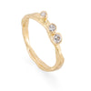 Upright front profile of a gold engagement ring with 3 diamonds set in it.