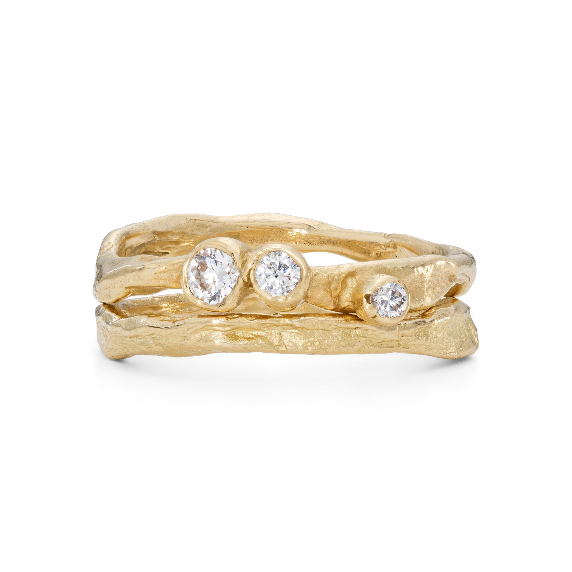 An 18ct gold ring in a craggy design, set with 3 diamonds. Photographed with a gold band sitting next to it, with a craggy texture.
