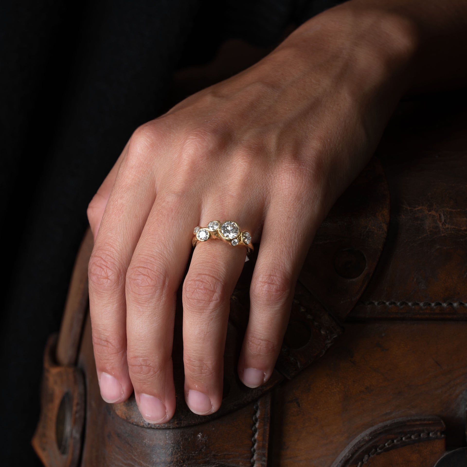 18ct gold and diamond engagement ring set in an unusual, sea worn texture, with 6 diamonds. Photographed on a models hand.