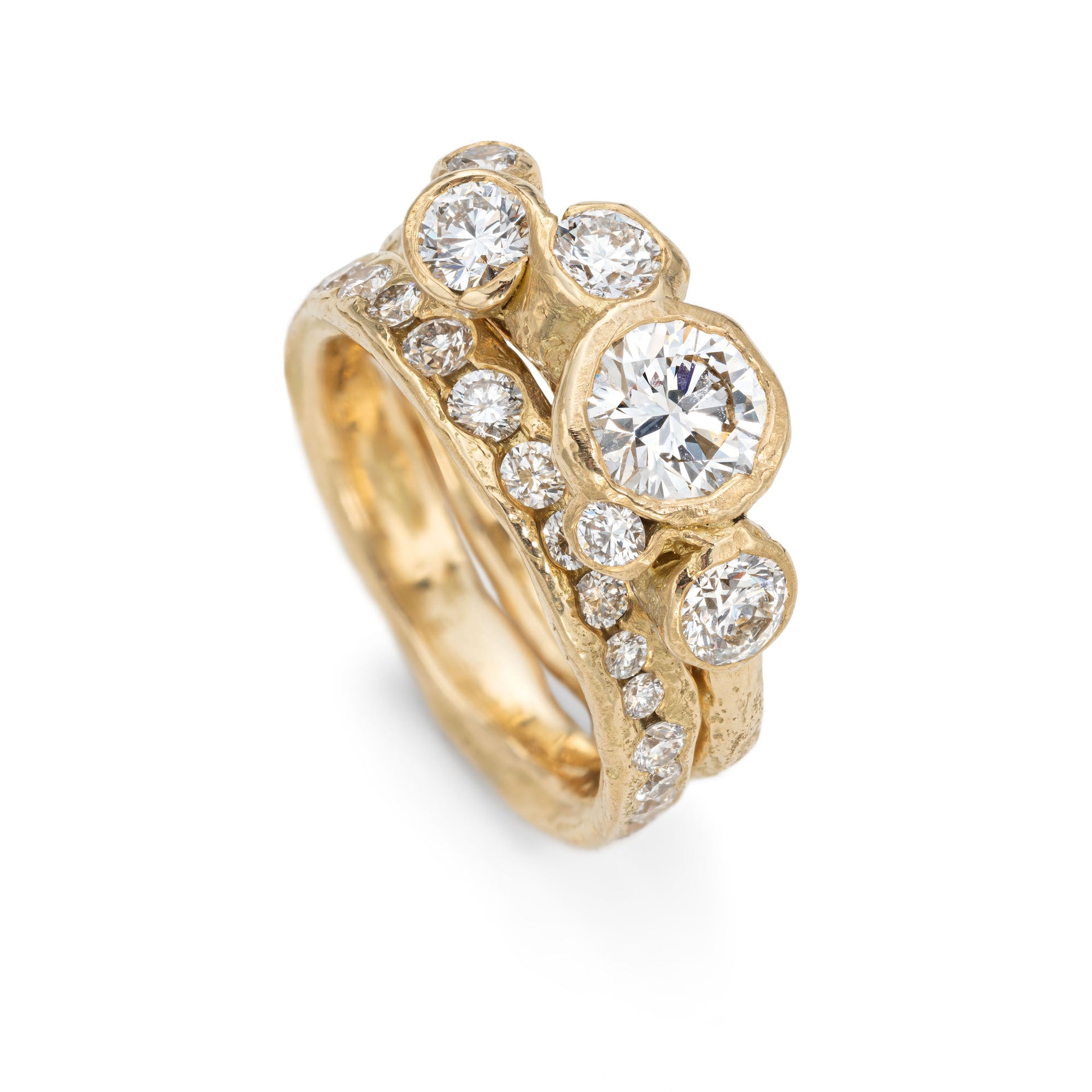 Upright, front view of an 18ct gold engagement ring, set with bright white six diamonds. Photographed next to a diamond channel ring, set with diamonds all the way around the ring.