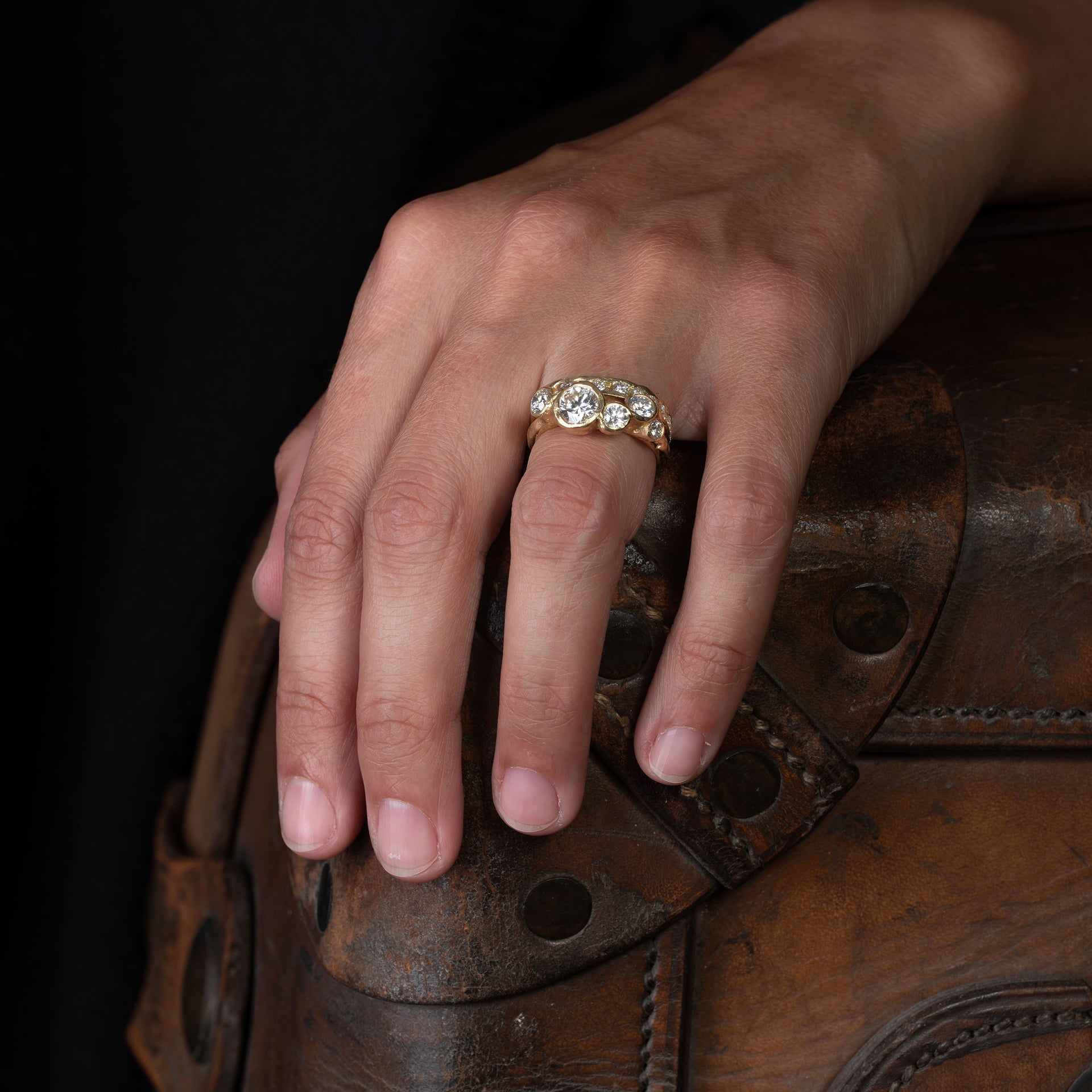 An organic and unusual 18ct gold engagement ring, set with 6 diamonds. Photographed on a models hand, sitting next to a diamond channel ring.