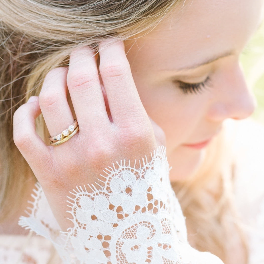 Handcrafted 18ct gold and diamond engagement ring, photographed on model. Also pictured is an 18ct gold band.