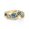 Unique handmade gemstone ring in recycled yellow gold with five teal sapphires and a brilliant white diamond.