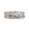 An alternative platinum engagement ring with 6 diamonds, sat next to a platinum ripple textured ring, by Emily Nixon.